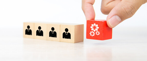 Hand choose gear icon on cube wooden toy block stack with people icon for business team creative thinking and human resources or person leader and teamwork or leadership team player.