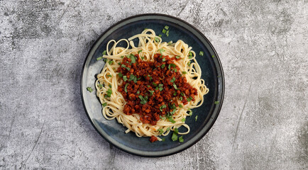 Traditional italian pasta bolognese with beef and tomato sauce  on a round plate on a dark gray background. Top view, flat lay