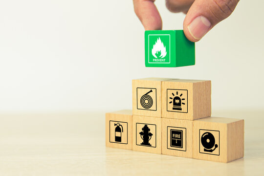 Fire prevention, Hand choose cube wooden block stack with door exit sing or fire escape with prevent icon and fire extinguisher and emergency protection symbol for safety and rescue in the building.