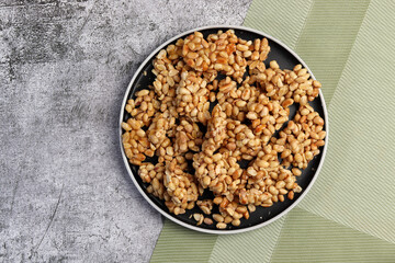 Homemade Peanut brittle  on a round plate on a dark gray background. Top view, flat lay