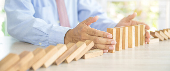 Close-up hand prevent wooden block falling domino concepts of financial risk management and...