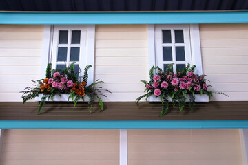Front of a wooden house plank wall with white windows  and flowers decorative on background