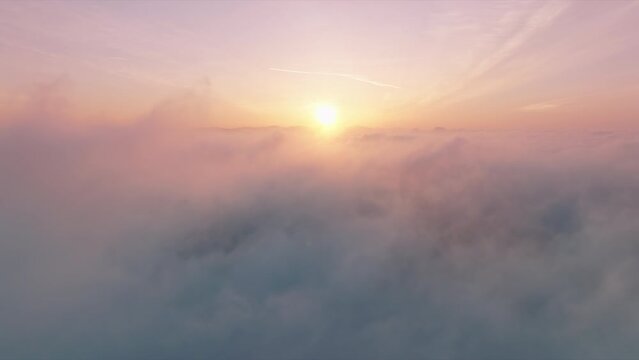 Flying through cinematic rose golden glowing cloudscape towards sunset sun. Flying in soft clouds. Aerial perspective view of flying over clouds. Sky with clouds and sun. Meditation dream footage 4K 