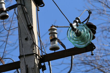 Close-up of high-voltage power lines and power pylons against a blue sky.