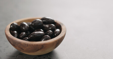 chocolate covered almonds in wood bowl with copy space