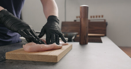 man hands rub spices into chicken fillet on oak board