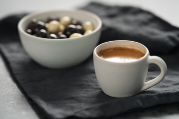 hot espresso in white cup and chocolate dragee on linen cloth with copy space