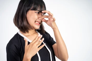 Foto op Canvas Young woman covering nose with finger when bad smell on isolated background © Odua Images