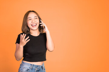 Young asian woman making a call using a cell phone on isolated background