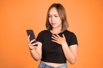 Fototapeta premium asian woman shocked while looking at her mobile phone on isolated background
