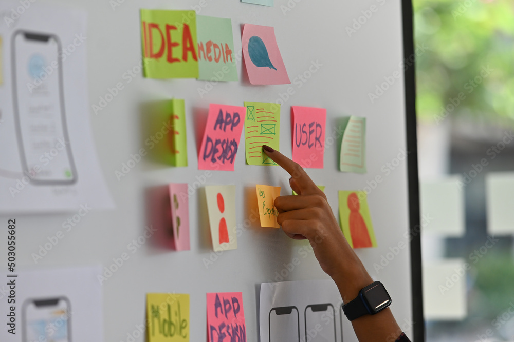 Poster side close up of a female finger pointing on a paper note while sharing her new ideas about a softwa
