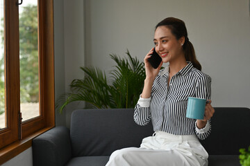 Young Indian Asian Female with a smiling face holding a cup of coffee while advising a customer on...
