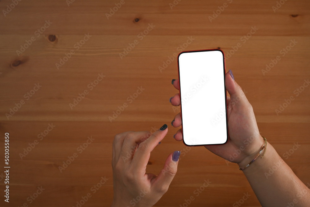 Poster Overhead top view of male hands using a smartphone with white blank screen desktop display ready for adding something over a wooden table as the background. Flat lay composition.
