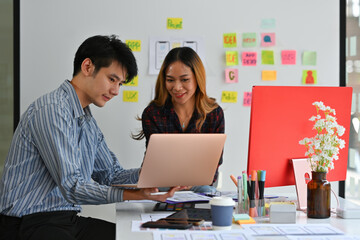 Asian business workers use the computer laptop for brainstorming a new creative media design with a...