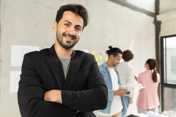 Successful handsome executive businessman architect smart casual wear looking at camera and smiling, arms crossed in modern office workplace.