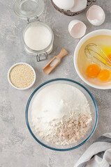 Ingredients for making sweet bread, brioche or challah bread. Yeast, flour, eggs, milk on a gray concrete background. Top view.
