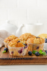 Lemon muffins with blueberries and shtreisel with fresh berries on a white wooden background. Delicious breakfast. Copy space.