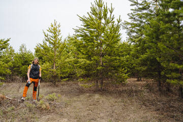 A guy stands in the forest, a man is dressed in camping equipment, a man is engaged in trekking in nature, hiking along the trails in the taiga, life outside the city.