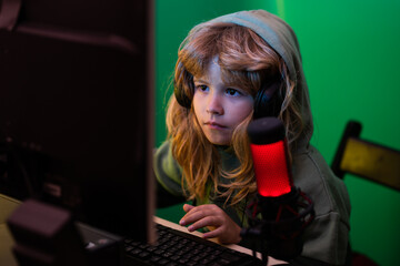 Cute preschool child watching video lesson by laptop. Little child blogger. A little boy child uses a desktop at night, a child with computer screen in the room with neon lightning.