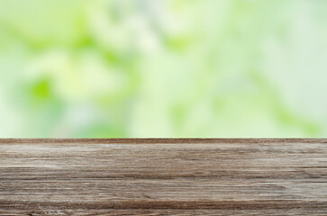 An empty brown wooden table. Blurry summer or spring background.