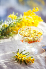 Traditional Russian mimosa salad with fish, eggs, potatoes and carrots.