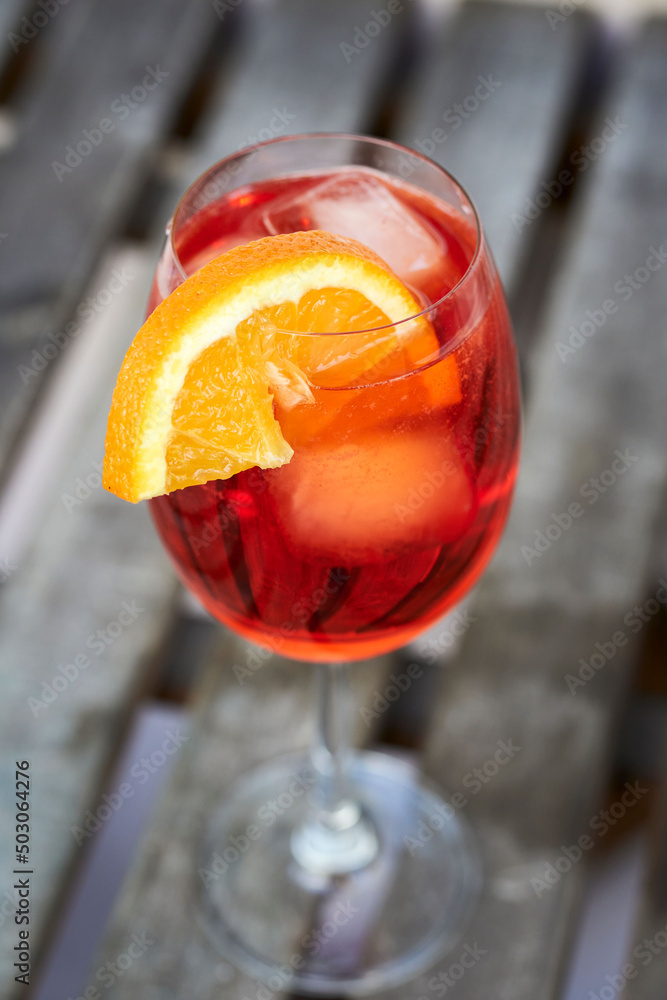 Sticker Closeup shot of a fresh Spritz Veneziano Cocktail with an orange slide on a woodenn board background