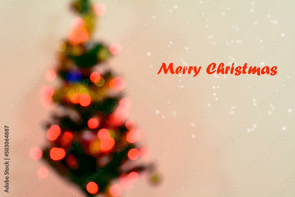 Poster merry christmas text in red with christmas tree and bokeh lights in the blurred background