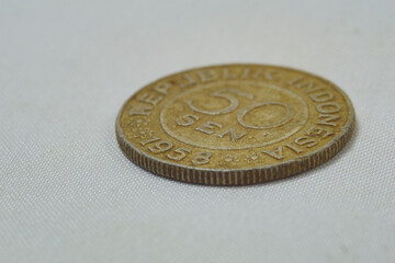 Closeup of a 50 sen Indonesian coin from 1958 on a white background © Lex Wanto Hutasoit/Wirestock Creators