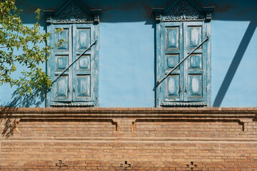 Old rustic country house with a blue-painted wall and closed shutters