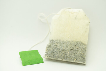 Teabag with green label. Isolated on white background. Close-up of tea bag. 