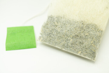 Teabag with green label. Isolated on white background. Close-up of tea bag. 
