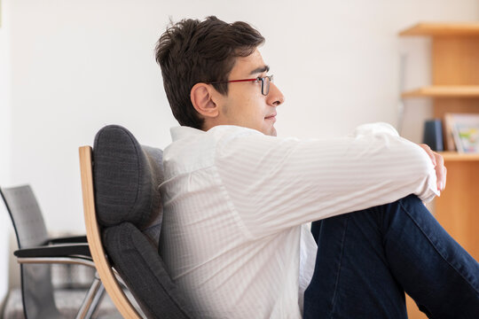 Junger Mann arbeitet in einem B&uuml;ro und macht Gedankenpause