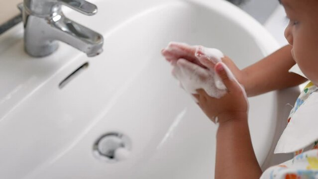 Small girl washing her hands to prevent virus, bacteria and germs at sink.