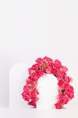 Spring pink flowers - roses as framing of arch with two podiums on abstract white stage mockup for showing of cosmetic products, goods, advertising, design, vertical. Fresh floral romantic background.