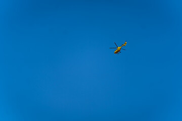 żółty ratunkowy helikopter na bezchmurnym niebie - obrazy, fototapety, plakaty
