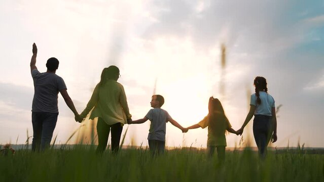 Big happy family. Summer people in park at sunset. Family is walk on green grass in natural park. Family fun, joy in nature. Healthy young family at sunset. Concept of happy people in nature in grass