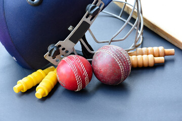 Old training cricket sport equipments on dark floor, leather ball, wickets, helmet and wooden bat,...