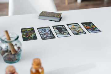 Naklejka na ściany i meble KYIV, UKRAINE - FEBRUARY 23, 2022: Tarot cards near blurred witchcraft supplies on table.