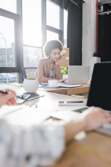 African american businesswoman using laptop near coffee in office.