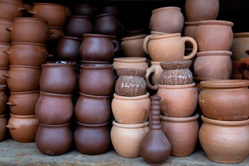 Fototapeta na wymiar Rows of traditional handmade clay pots and earthenware jar on market or bazaar. Organic way making earthen pottery to store wine or olive oil, as well as everyday objects.