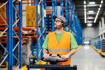 A storage worker with headset driving forklift.