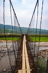 isolated iron suspension bridge old with misty mountain background at morning