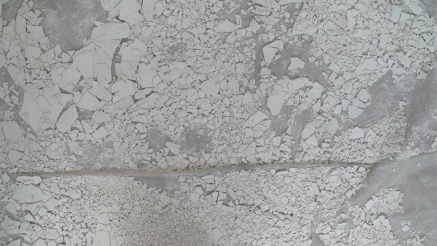 Old, cracked putty on the floor. The crumbling white plaster from the ceiling lies on the floor.