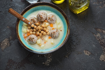 Turquoise bowl with turkish chickpea and meatball soup, above view on a brown stone background, horizontal shot