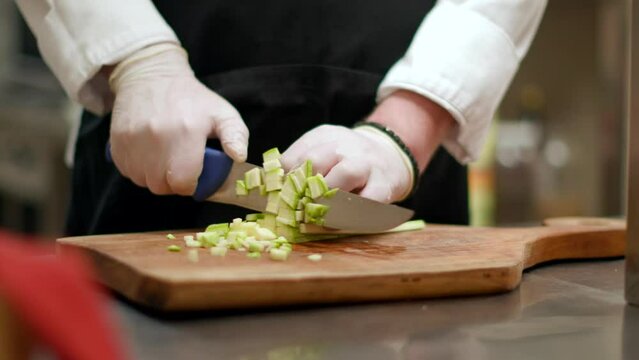 A person in white gloves delicately cuts up a piece of lettuce with precision.
