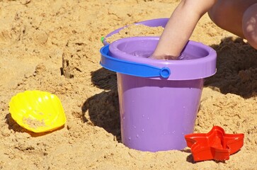 Fototapeta na wymiar Child playing with a plastic bucket on the beach 