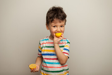 Cute boy eating lemon over a white background