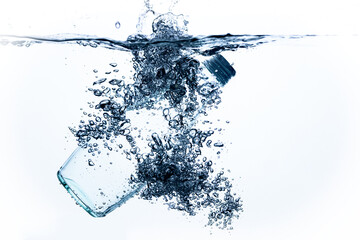 a bottle of drinking water falls into the water on a white background