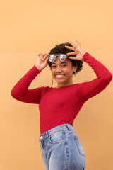 A Young latin woman posing and smiling in front of orange wall with sunglasses, Panama, Central America