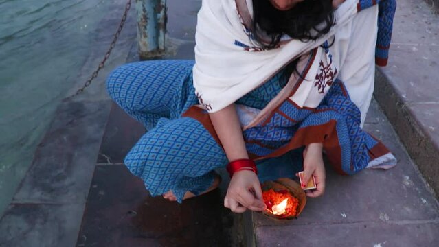 young girl devotee lighting oil lamps to offer holy river ganges at evening from top angle